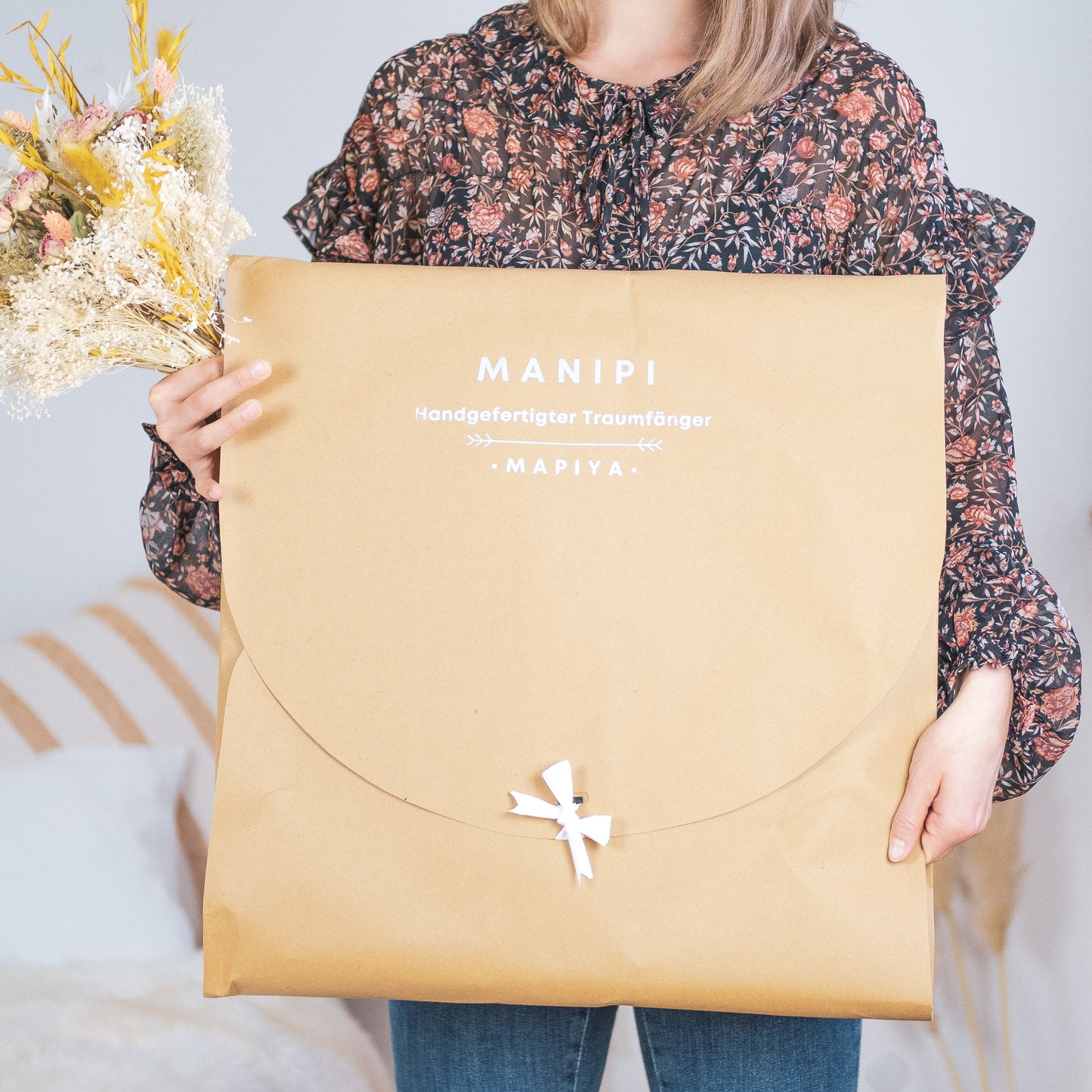 Eine junger Frau präsentiert die XXL Geschenkverpackung eines Wandbehangs im Boho-Stil.