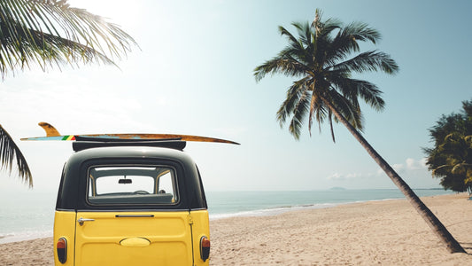 Ein alter gelber VW Bus steht am Venice Beach mit Palmen und Sonne